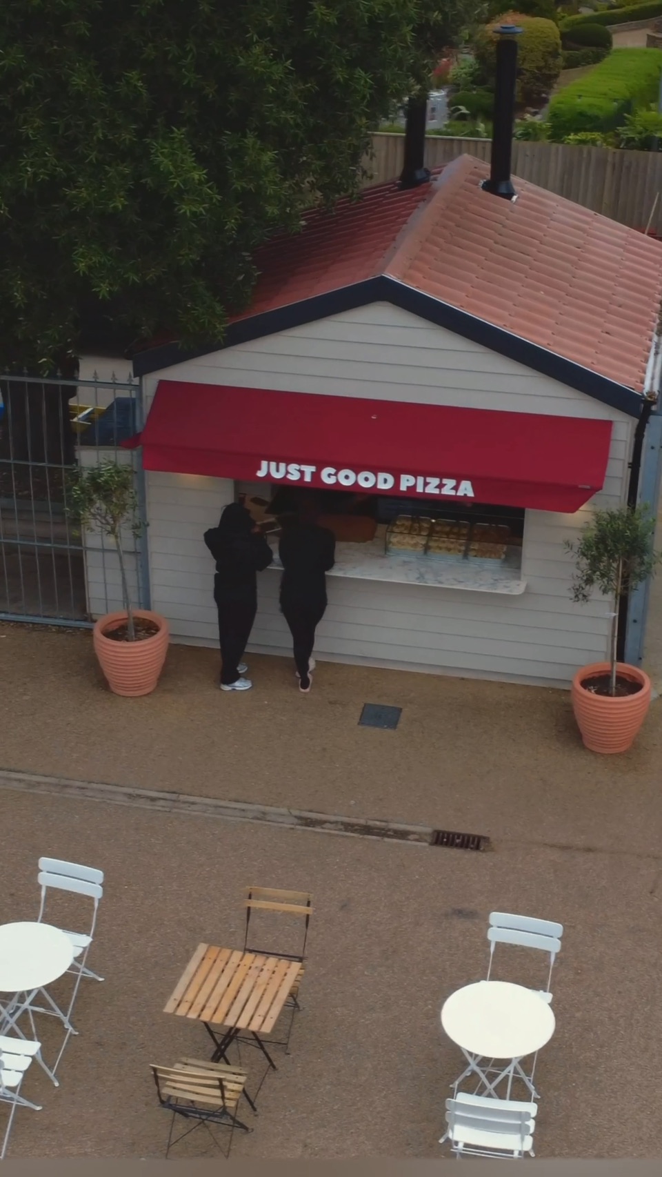 The Dough Boys kiosk seen from above, its red awning out and two customers at the hatch