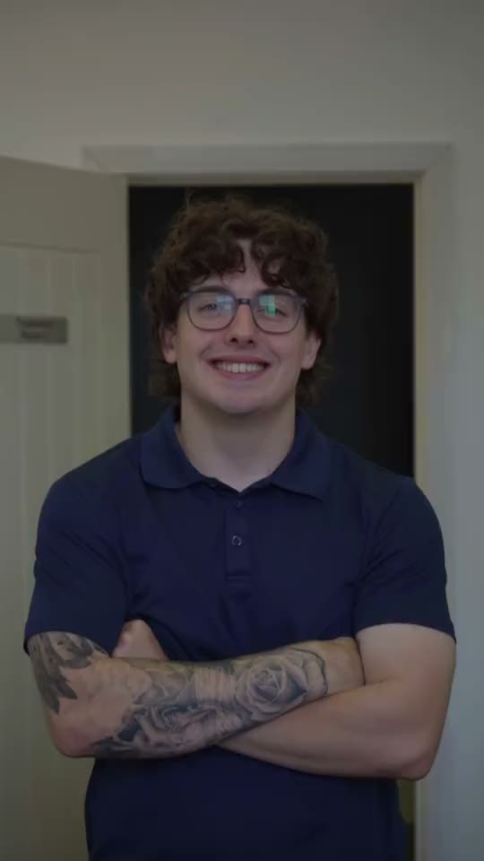 A chiropractor smiling at the camera, arms folded, in the clinic