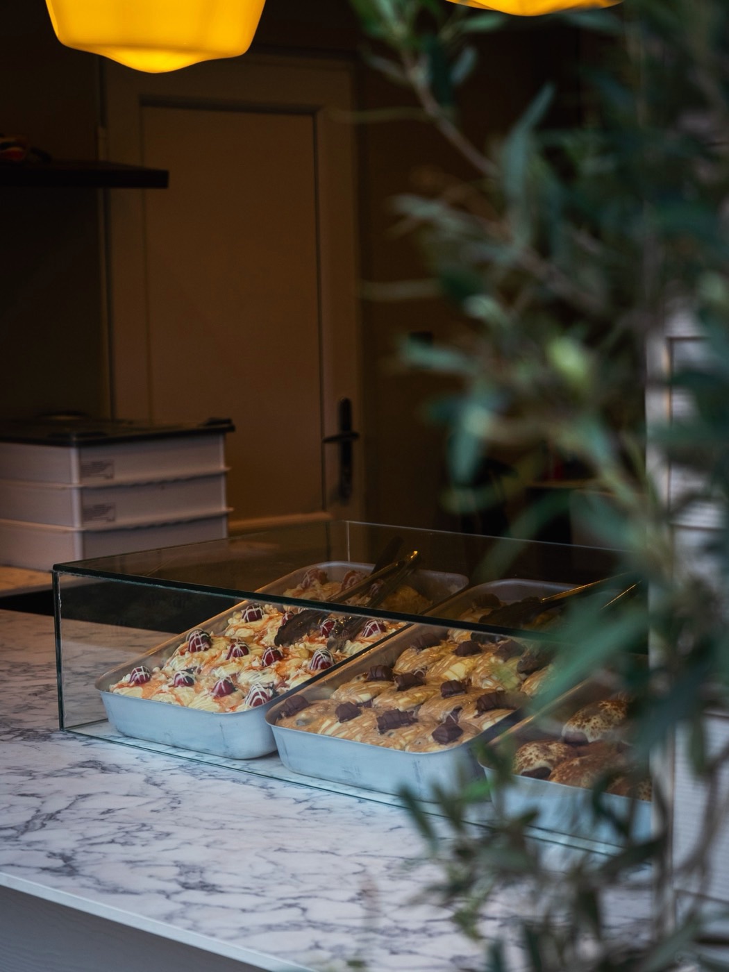 Trays of dough desserts under the glass counter, topped with raspberries and chocolate