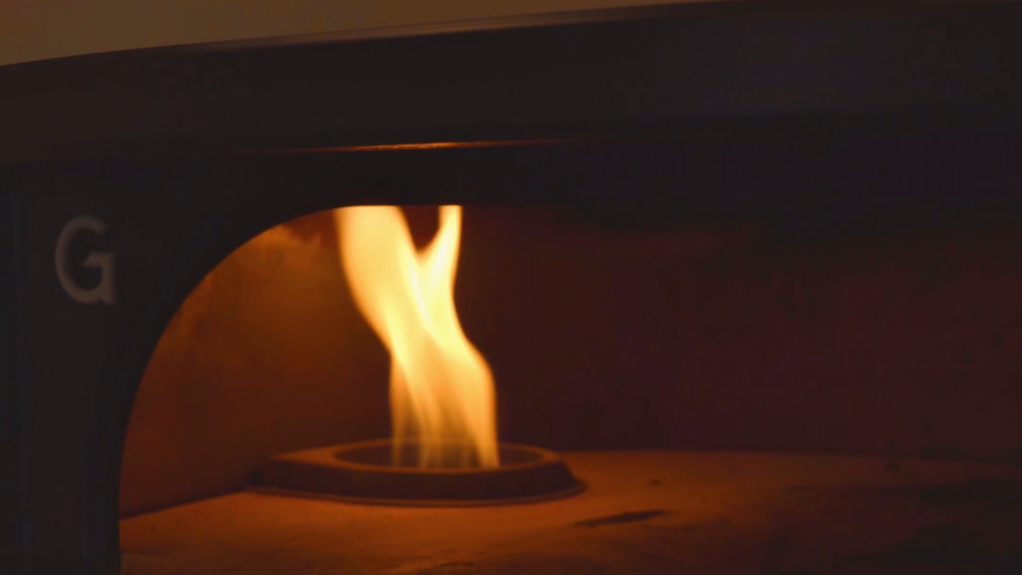 A flame burning at the back of the pizza oven